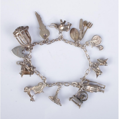 495 - A silver charm bracelet featuring eleven charms including Beefeater, Elephant, Cutlery, Key, Birdcag... 