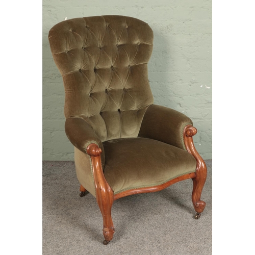 575 - A Victorian button back armchair with green upholstery and scrolling mahogany frame on brass casters