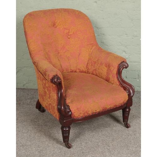 577 - A Victorian mahogany armchair with scrolling frame on brass castors.