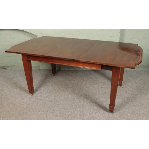 589 - A mahogany inlaid dining table with square tapering legs sat on brass castors. Comes with one additi... 