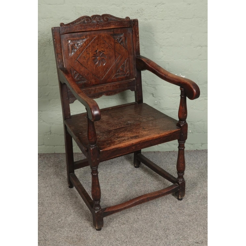 545 - An oak wainscot armchair with carved detail to panel.