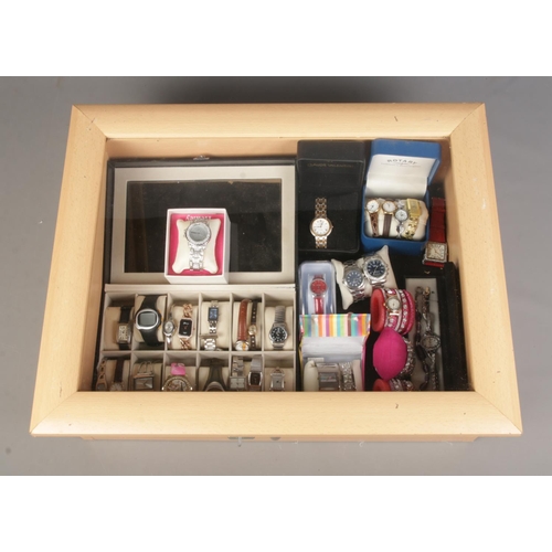 110 - A table top display case containing an assortment of watches, mainly quartz examples. To include Gen... 