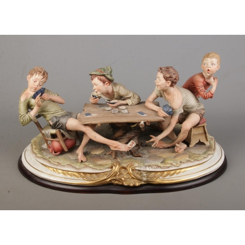 156 - A large Capodimonte figure group titled 'The Cheat' raised on wooden plinth.