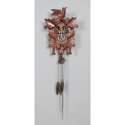 346 - A German cuckoo clock with weights and wooden pendulum. 43cm from base of clock to top of pediment.