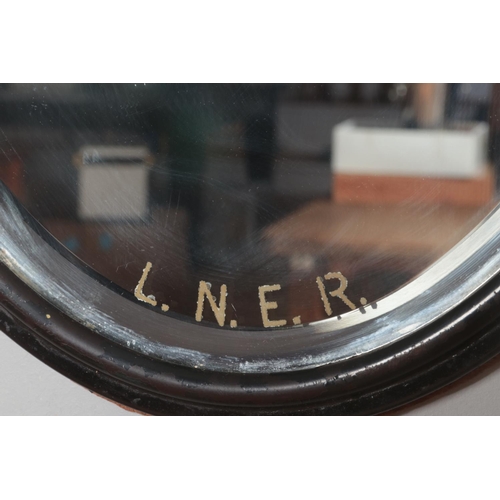 379 - An oval framed bevel edge L.N.E.R. mirror. Height: 42cm, Width: 32cm.