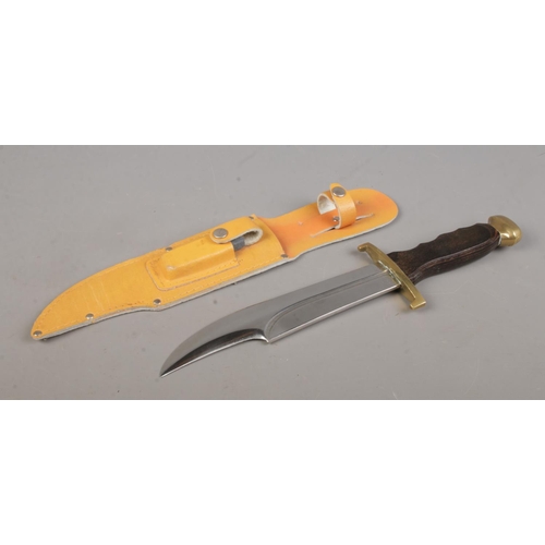 77 - A 'Crocodile Hunter' bowie knife in sheath, with sharpening stone. Blade length 8.25 inches. CANNOT ... 