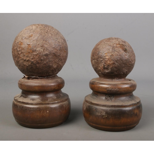 88 - Two similar canon balls on wooden turned mounts.