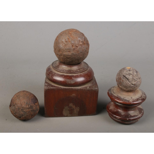92 - Three small canon balls with two mounted on wooden bases.