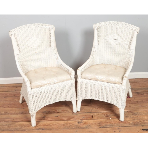 486 - A pair of cream wicker patio chair with cushioned seats.