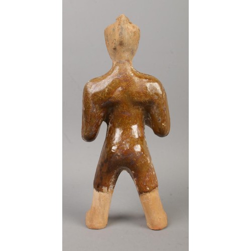 465 - A partially glazed Chinese terracotta tomb figure formed as a servant with outstretched arms. Purpor... 