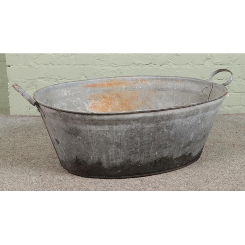 276 - An oval galvanised tin bath, with twin handles. Height: 32cm, Width: 102cm.