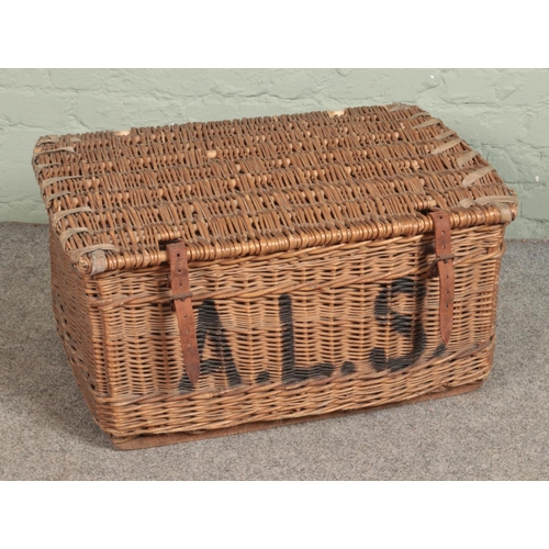 282 - A large wicker basket stamped A.L.S to front with leather strap closures. Approx. dimensions 75cm x ... 