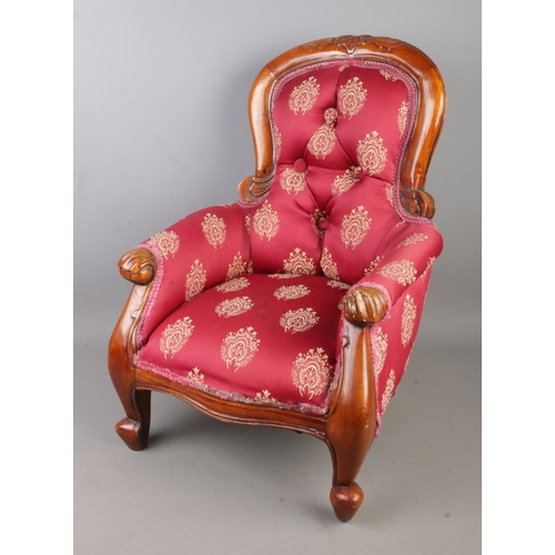 306 - An upholstered button back child's/dolls chair featuring carved floral motif.