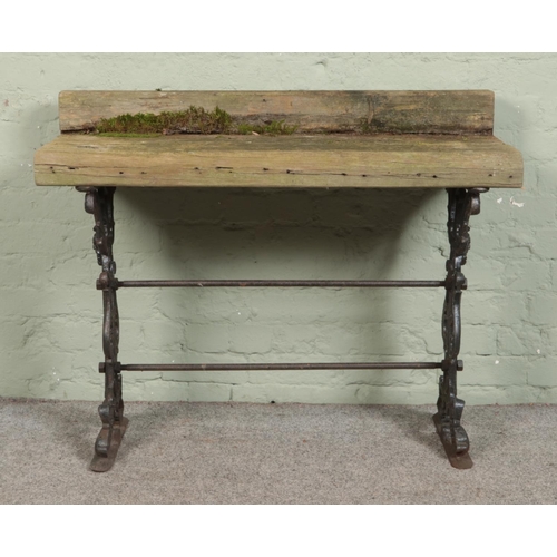 323 - A garden table composed of sleepers, on cast iron base. Height: 85cm, Width: 107cm, Depth: 43cm.