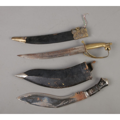 65 - An Indian Kukri knife, together with a similar example stenciled 'Ancient Asia', both in sheaths. CA... 