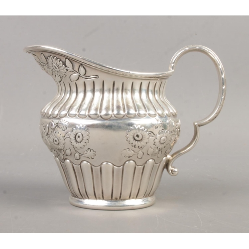 458 - An early Twentieth Century silver cream jug, heavily engraved with floral detailing to the central b... 