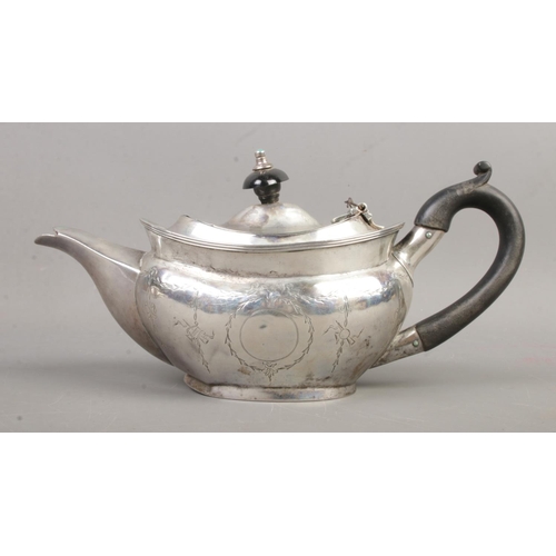 459 - An Edwardian silver teapot of squat form, featuring ebonised handle, swag and bow engraving and blan... 