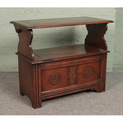 517 - A carved oak monks bench, with detailing to back rest and front. Featuring folding top and under sea... 