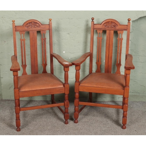 501 - A pair of oak carved open armchairs with drop in leather seats.