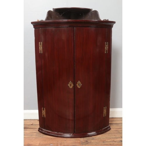 525 - A mahogany bow fronted corner cupboard with upper tier. Height 102cm, Width: 68cm.