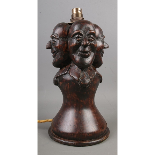 86 - A wooden Folk Art table lamp, with four mask decoration. (Height approximately 29cm).