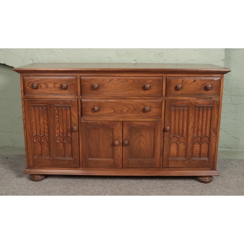 536 - An Ercol elm Canterbury dresser base having a combination of four drawers and three cupboard doors 
... 