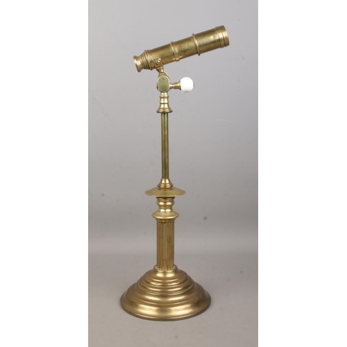 10 - A brass four drawer desk telescope, with cogged swivel movement, mounted to a Corinthian column rais... 