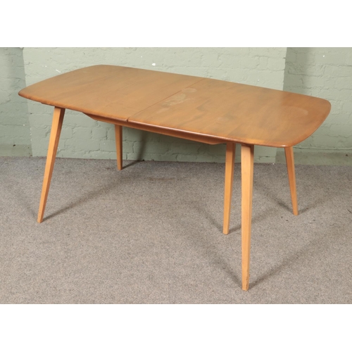 563 - An Ercol 'Grand Windsor' light oak and ash extending dining table, with hinged additional leaf, roun... 