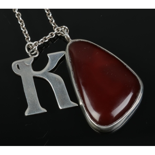 414 - A silver mounted carnelian pendant and silver K pendant on chain.