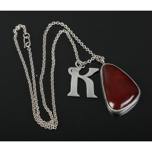 414 - A silver mounted carnelian pendant and silver K pendant on chain.