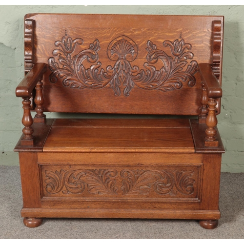 529 - A carved oak monks bench, with detailing to back rest and front. Featuring folding top and under sea... 