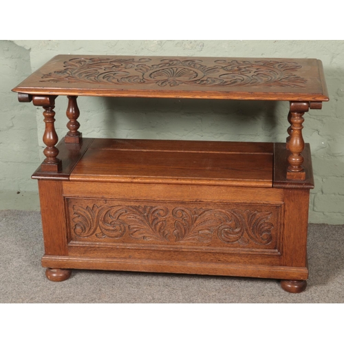 529 - A carved oak monks bench, with detailing to back rest and front. Featuring folding top and under sea... 