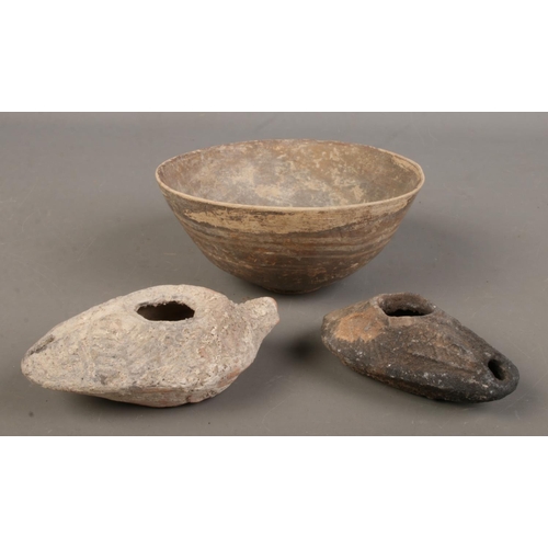 482 - Two Romanesque oil burners along with a terracotta bowl.