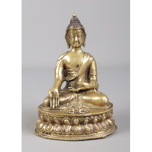 7 - A 19th century Sino Tibetan bronze devotional statue of a seated Buddha raised on lotus plinth.