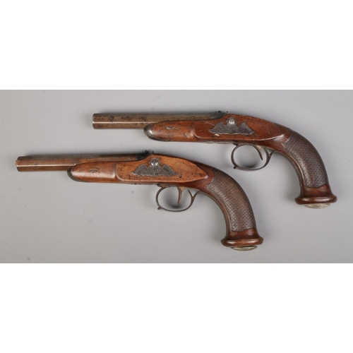 100 - A pair of 19th century percussion pistols. Having chequered walnut grips and damascus octagonal barr... 