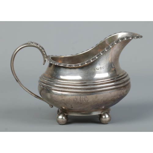 128 - An early 19th century silver cream jug. With gadrooned rim and raised on four ball feet. Assayed New... 