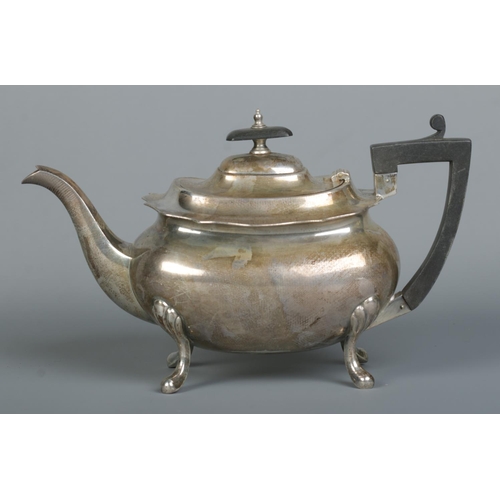 150 - A George V silver teapot. Raise on four scrolling feet and having ebonised finial and handle. Presen... 