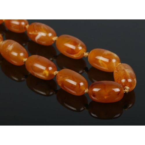 178 - A string of graduated butterscotch amber beads with yellow metal clasp. Largest bead approximately 2... 