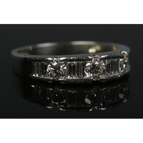 202 - A platinum and diamond ring. Channel set with eight baguette and three brilliant cut diamonds. Size ... 