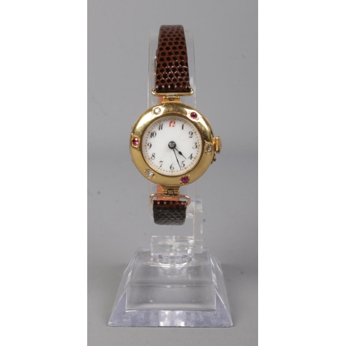 213 - A ladies 18ct gold, diamond and ruby manual wristwatch on leather strap with 9ct gold buckle.