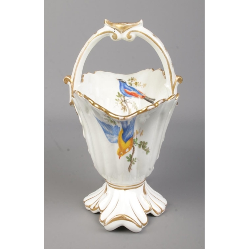 29 - A Rockingham helmet shaped basket with arched handle. With hand painted exotic birds in the manner o... 