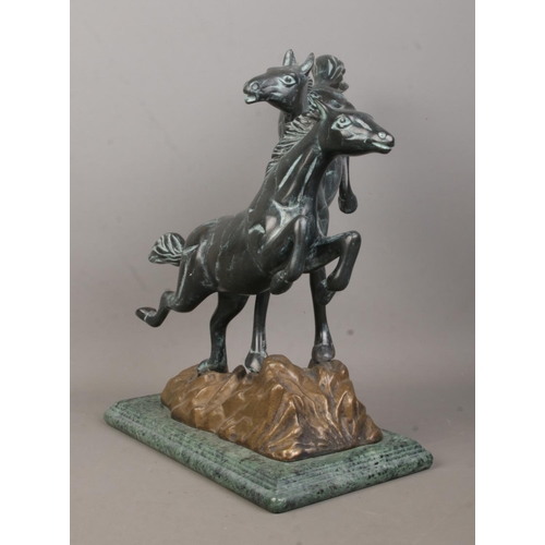 58 - A Verdi Gris bronze sculpture modelled as two frolicking horses raised on marble base. Height 30.5cm... 