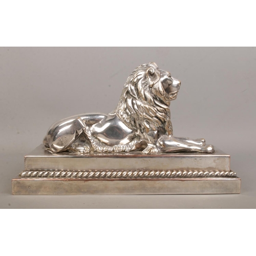 59 - A silverplated bronze sculpture of a lion raised on stepped plinth. Height 16cm, Length 28.5cm.