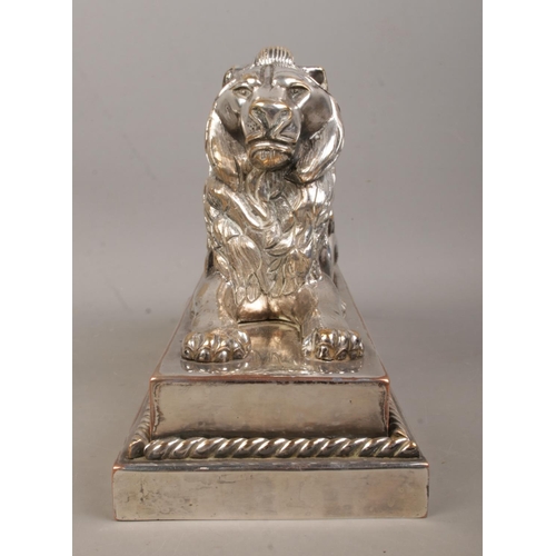 59 - A silverplated bronze sculpture of a lion raised on stepped plinth. Height 16cm, Length 28.5cm.