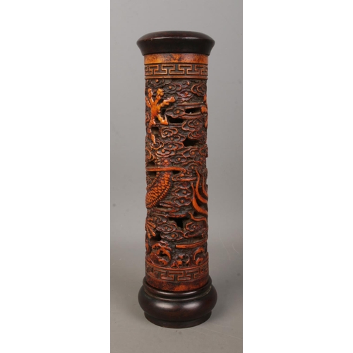 6 - A Chinese wooden incense holder with carved decoration depicting dragons. Height 25cm.