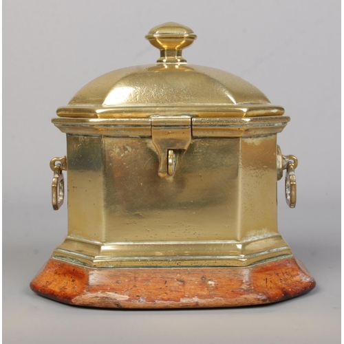 61 - A Georgian brass tobacco box of sarcophagus form, raised on wooden plinth. Height 14cm.