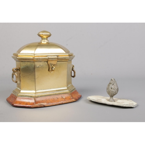 61 - A Georgian brass tobacco box of sarcophagus form, raised on wooden plinth. Height 14cm.