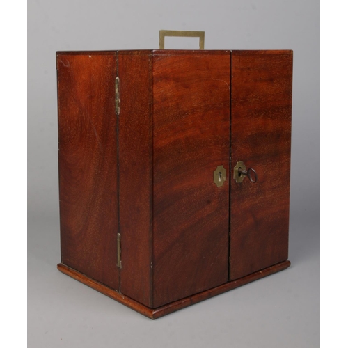 63 - An early 19th century mahogany apothecary cabinet with double door front. Having brass campaign styl... 