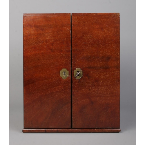 63 - An early 19th century mahogany apothecary cabinet with double door front. Having brass campaign styl... 