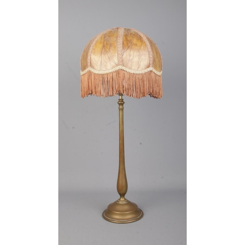 75 - A brass rise and fall table lamp in the style of Benson with fringed shade.